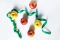 Healthy food concept - fresh fruits and measuring tape, apples and weight loss on a white background.
