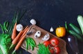 Healthy food concept with fresh vegetables on a dark background: tomato, zucchini, onion, lettuce, dill, pepper, cucumber, garlic Royalty Free Stock Photo