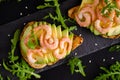 Healthy food concept. Toasts with avocado, shrimps and arugula on black background.