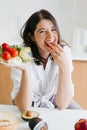 Healthy food concept. Young happy woman eating cherry tomato and holding plate with green lettuce, arugula and tomato on Royalty Free Stock Photo