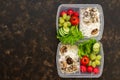 Healthy food in containers, rice with mushrooms and vegetables on dark background, top view. Copy space.