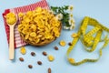 Healthy food cornflakes in a wicker plate on a red towel with chamomile flower, centimeter tape and wooden spoon