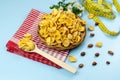 Healthy food cornflakes in a wicker plate on a red towel with chamomile flower, centimeter tape and wooden spoon