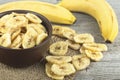 Healthy Food - Dried banana slices and fresh bananas on wooden table. Banana chips. Royalty Free Stock Photo