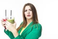 Healthy Food Eating. Choosy Thinking Woman With Both Green and Red Detox Vegetable Smoothie. Posing in Green Jacket Over White. Royalty Free Stock Photo