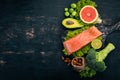 Healthy food. Fish salmon, avocado, broccoli, fresh vegetables, nuts and fruits. On a black background.