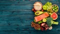 Healthy food. Fish salmon, avocado, broccoli, fresh vegetables, nuts and fruits. On a wooden background. Royalty Free Stock Photo