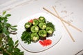 Fresh raw food dish. Green rolls of grape leaves with vegetable filling on white plate on shabby white surface.