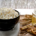 Healthy food: homemade cheese in a black round plate stands on a wooden table next to a jar of honey