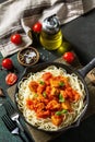 Healthy food, Italian pasta. Spaghetti with chicken and vegetables in tomato sauce in a cast iron skillet on a stone countertop. Royalty Free Stock Photo