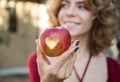 Healthy food and lifestyle - beautiful woman holds in her hand a red apple with a heart cut in it Royalty Free Stock Photo