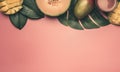 Healthy food, melon, mango and smoothies are laid out on a monstera leaf, on a pink background, space for text flat lay