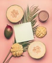 Healthy food, melon, mango and smoothies are laid out on a tropical leaf, with a postcard and space for text, on a pink background Royalty Free Stock Photo