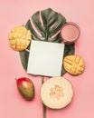 Healthy food, melon, mango and smoothies are laid out on a tropical leaf, with a postcard and space for text, on a pink background Royalty Free Stock Photo