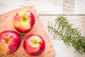 Healthy food: red apples and rosemary on wooden table