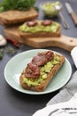 Healthy food. Rye bread with guakomole, avocado pasta and dried tomatoes, on wooden cutting board. Avocado toast Royalty Free Stock Photo