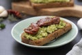 Healthy food. Rye bread with guakomole, avocado pasta and dried tomatoes, on wooden cutting board. Avocado toast Royalty Free Stock Photo