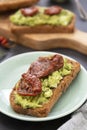 Healthy food. Rye bread with guakomole, avocado pasta and dried tomatoes, on wooden cutting board. Avocado toast Royalty Free Stock Photo