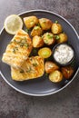 Healthy food serving grilled fish cod with baked potatoes, sauce and lemon close-up in a plate. Vertical top view Royalty Free Stock Photo