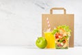 Healthy food set with fresh orange juice, tropical salad with shrimps, vegetables, apple in plastic packaging, packet in white. Royalty Free Stock Photo