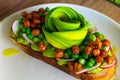 Healthy food - a slice bread dressed with hummus topping, flower-shaped of avocado, green beans, beetroot, roasted peanut.