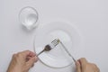 Healthy food theme: hands holding knife and fork on a plate with green peas on a white table top view Royalty Free Stock Photo