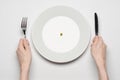 Healthy food theme: hands holding knife and fork on a plate with green peas on a white table top view Royalty Free Stock Photo