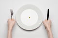 Healthy food theme: hands holding knife and fork on a plate with green peas on a white table top view Royalty Free Stock Photo