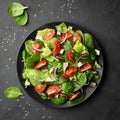 Top view of a fresh green vegetable salad of spinach, tomato, lettuce and sesame seeds