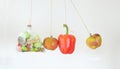 Healthy food versus unhealthful sweets, apples and bell pepper bouncing against bag of junk food, conceptual image, isolated on Royalty Free Stock Photo