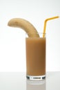 Healthy food and vitamins: a cleared ripe yellow banana in a glass beaker with banana juice with a cocktail straw, on a table on Royalty Free Stock Photo