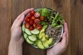 Healthy food. Womans hand holding budha bowl with quinoa, avocado, cucumber, salad, tomatoe, olive oil. Clean eating, diet food.