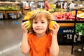 Healthy food for young family with kids. Portrait of funny little child holding shopping bag full of fresh vegetables. A Royalty Free Stock Photo