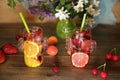 Healthy fresh fruits and berries smoothies in glass bottles with straws on a rustic wooden table decorated with flowers and fruits Royalty Free Stock Photo