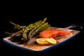 Healthy fresh green asparagus, raw salmon and lemon slices on a wooden cutting board with a black background Royalty Free Stock Photo