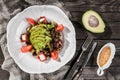 Healthy fresh salad with avocado, greens, arugula, cherry tomatoes, olives and cheese in plate over rustic wooden table Royalty Free Stock Photo