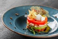 Healthy fresh salad with avocado, tiger prawns, capers, tomato, poached egg in plate over dark table. Healthy vegan food, clean