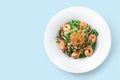 Healthy fresh salad with lettuce, greens, nuts, shrimp and sauce in plate on isolated blue background. Healthy food, clean eating Royalty Free Stock Photo