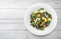 Healthy fresh salad with mix greens, apple, cream cheese, cranberry, sauce and edible flowers in plate on light wooden background Royalty Free Stock Photo