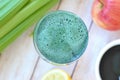 Healthy fresh smoothie drink from red apple, green algae spirulina, lemon, and celery in the glass on wooden background Royalty Free Stock Photo