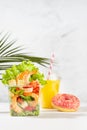 Healthy fresh summer tropical breakfast take away - set of orange juice, salad with shrimps, red pepper, lettuce, croutons, pink.