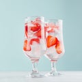 Healthy fresh tonic with strawberry slices, ice cubes, soda in misted glass on white wood table, pastel green color background.