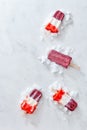 A healthy fruit colored ice cream on a stick with ice cubes on a gray marble table with a copy of the space for text Royalty Free Stock Photo