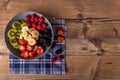 Healthy fruit salad in a greyblue plate on wood antique table and retro blue tablecloth