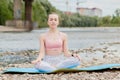 Healthy girl relaxing while meditating and doing yoga exercise in the beautiful nature on the bank of the river Royalty Free Stock Photo