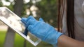 A healthy girl is walking in medical gloves working with a tablet in a city park. close-up. COVID-19. danger of virus Royalty Free Stock Photo