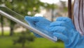 A healthy girl is walking in medical gloves working with a tablet in a city park. close-up. COVID-19. danger of virus Royalty Free Stock Photo