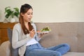 Healthy Asian girl eating her healthy salad while relaxing in her living room Royalty Free Stock Photo