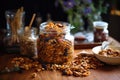 Healthy granola in a glass jar spilling onto wooden table with dried fruits and nuts