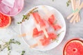 Healthy grapefruit and thyme ice pops, overhead table scene against marble